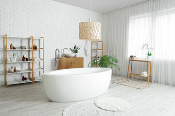 Stylish bathroom with bathtub, chest of drawers, shelving unit and lamp