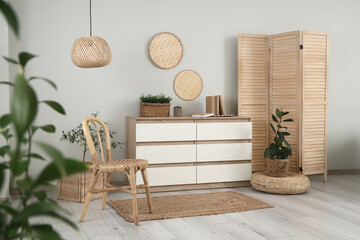 Interior of light living room with wooden folding screen, chair and commode