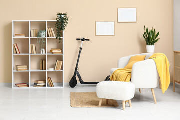 Electric scooter, armchair and bookcase near beige wall in living room