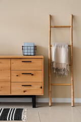 Wooden chest of drawers and ladder in stylish room