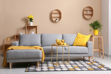 Interior of modern living room with grey sofa, yellow pillow and oranges on coffee table