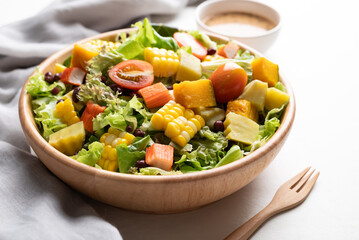 Colorful vegetable salad in a rustic wooden bowl with Japanese sesame dressing on white background, Healthy, fresh, plant based eating concept