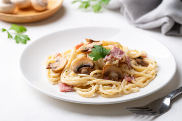 Spaghetti carbonara with ham, bacon and champignon mushroom on plate with white background, Italian food