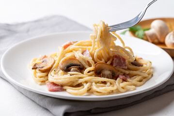 Spaghetti carbonara with ham, bacon and champignon mushroom on plate with white background, Italian food