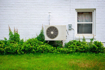 mini split air conditioner / heat pump exterior unit mouted ground floor  brick wall white of older...
