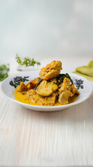 A rich and aromatic plate of Gulai Jengkol, a traditional Indonesian curry featuring tender Jengkol (dogfruit) and chicken in a creamy, spicy coconut milk sauce.


