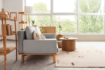 Interior of modern living room with grey sofa, shelving units and coffee table