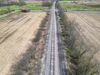 Railroad tracks through a cornfield as seen from a drone in Columbus, Pennsylvania, USA on a sunny spring day