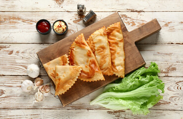Composition with tasty chebureks on light wooden background, top view