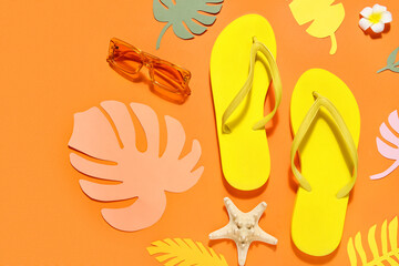 Composition with stylish beach shoes, sunglasses and paper leaves on orange background, closeup