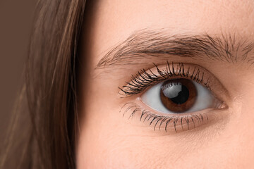 Fototapeta premium Woman with brown eyes on color background, closeup