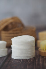 Cotton pads and body brushes arranged on wooden surface