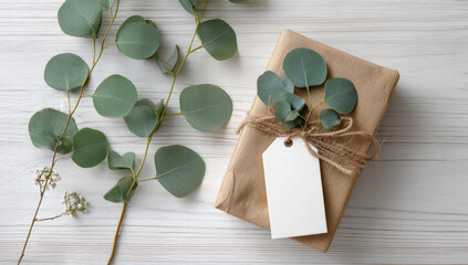 Gift wrapped in brown paper with eucalyptus leaves and blank tag on wooden surface
