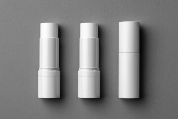 Three white lipstick-like products on gray background
