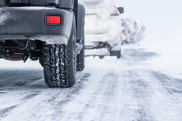 Cars driving on snowy road with snow-covered tires