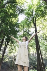 A woman standing in the forest with arms outstretched enjoying nature