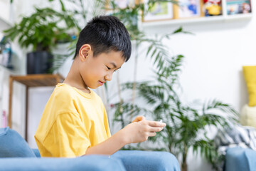 Young boy sitting on sofa using mobile phone indoors