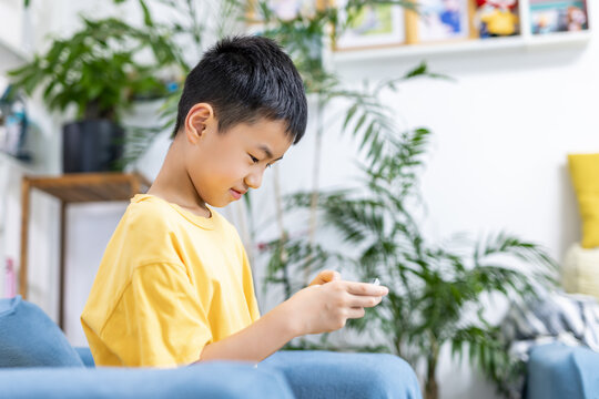 Young boy sitting on sofa using mobile phone indoors
