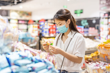 Woman wearing mask shopping in supermarket selecting items