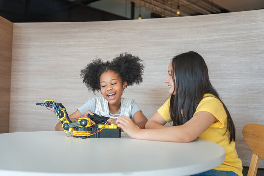 Cheerful Young Girls Engaged in Robotics and STEM Learning, Diverse Kids Building a Robot Arm in a Science Workshop, Two Girls Exploring Technology and Innovation