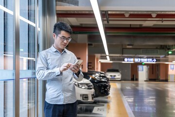 A man using a mobile phone in an indoor parking lot