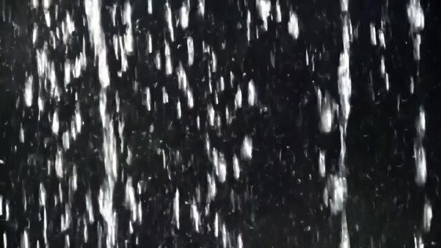 Seamlessly looped close-up animation of vertical falling rain, realistic raindrops forming a dense rain wall. Real rainstorm VFX insert style. Dark black background. 4K resolution, ultra-detailed, cin