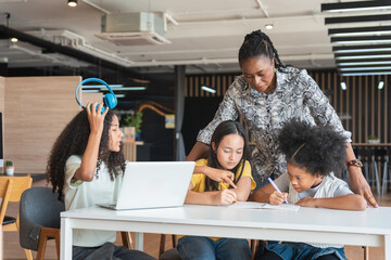 Educator Assisting Children with Schoolwork and Laptops, Multi-ethnic Group of Kids Learning...