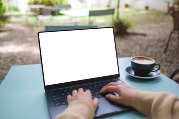 Mockup image of a woman working and typing on laptop computer with blank white desktop screen in...