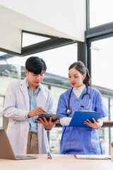 Two medical professionals discussing patient information with digital tablet and clipboard in...
