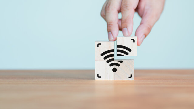 Wi-Fi icon on wooden cube block for service in the cafe. Hand put a wifi icon on wooden cube on wood table. Business communication social network, Wireless network and connection technology concept. - Powered by Adobe
