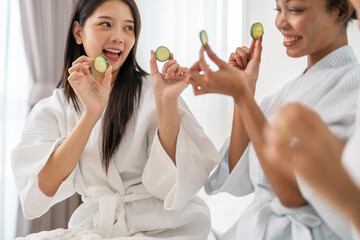 Diverse group of beauty women enjoy skincare routine, applying cucumber eye masks for hydration and...
