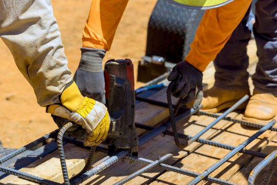 Workers collaborate to secure rebar on wooden mold at construction site under construction work day