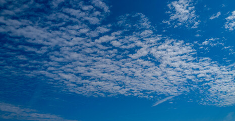 Background with clouds on blue sky. Sky view. Beautiful sunny sky. Clouds on blue sky. Sun shining through the puffy clouds.