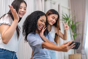 Diverse group of female friends taking selfie with smartphone smiling and posing for social media post, capturing happy and fun moments together, technology, joyful expressions and laughter at home