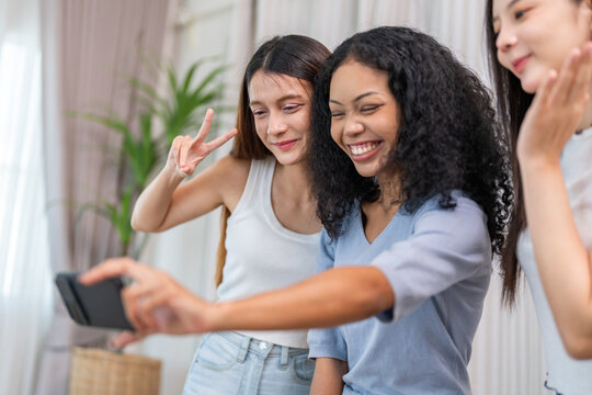Diverse group of female friends taking selfie with smartphone smiling and posing for social media post, capturing happy and fun moments together, technology, joyful expressions and laughter at home