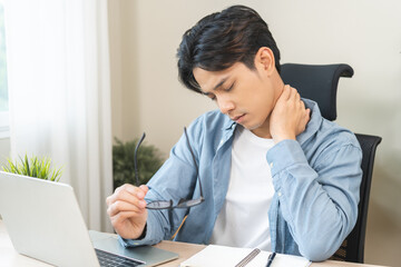 Body muscles stiff problem, ache asian young man pain neck and shoulder while sitting work on chair...