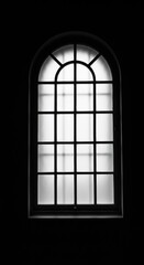 Fototapeta premium A beautiful arched window with frosted glass and a dark frame is set against a black background