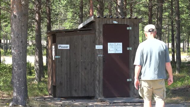 Are, Sweden A man uses an outhouse in parking lot. 