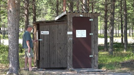 Are, Sweden A man uses an outhouse in parking lot. 