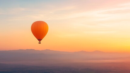 Obraz premium Vibrant orange hot air balloon floats over misty mountains at sunrise