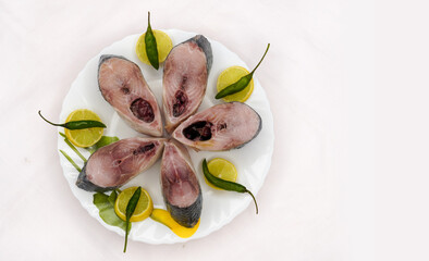 Slices of fresh raw hilsa fish on brass plate, ready for cooking. The famous ilish fish of the...