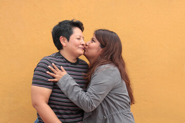Two dark-skinned Latina lesbians are a couple and show their love with kisses and hugs to celebrate LGBTQ Pride
