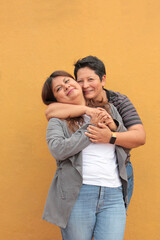 Two dark-skinned Latina lesbians are a couple and show their love with kisses and hugs to celebrate...