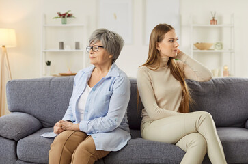 Portrait of offended upset adult daughter and senior elderly mother ignoring each other after...