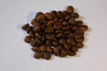 Roasted brown coffee beans, isolated on a white background, form a heap, ready for a rich, dark espresso drink