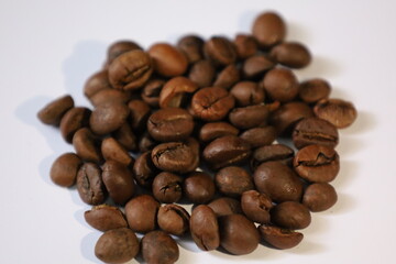 Roasted brown coffee beans, isolated on a white background, form a heap, ready for a rich, dark espresso drink