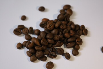 Roasted brown coffee beans, isolated on a white background, form a heap, ready for a rich, dark...