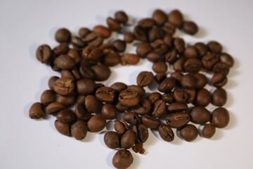 Roasted brown coffee beans, isolated on a white background, form a heap, ready for a rich, dark espresso drink