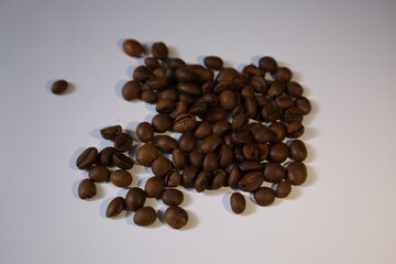 Roasted brown coffee beans, isolated on a white background, form a heap, ready for a rich, dark espresso drink