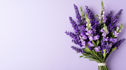 Obraz premium Bouquet of purple wildflowers with green leaves on light purple background, fresh and vibrant floral arrangement